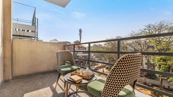 A balcony with two chairs, a small table with a tray, and a view of the cityscape.