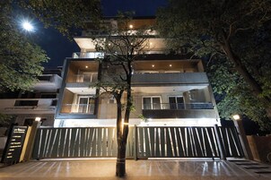 A multi-story building with a gated entrance, balconies, and trees.
