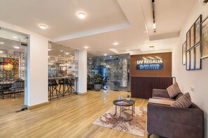 A modern interior with a reception desk, seating area, and a sign for LIV REGALIA ALAYA STAYS BY ELIVAAS. - Alaya Stays Liv Regalia Apartments (Gurugram)