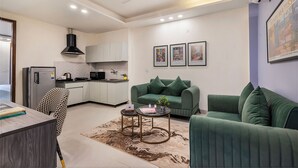 A modern living room with a green sofa, a coffee table, and a dining area with a chair and table.
