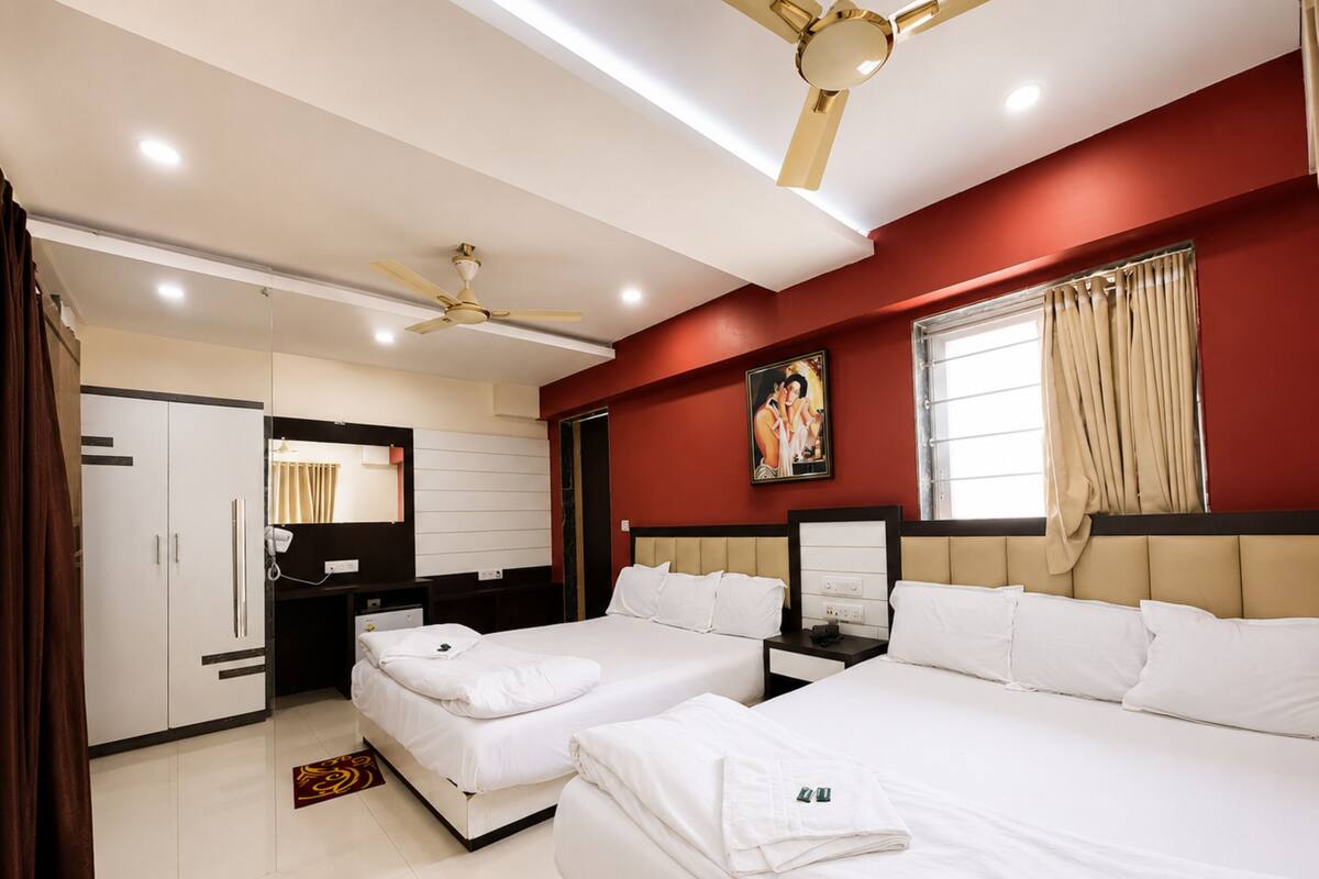A hotel room with two beds, a ceiling fan, a large mirror, and a painting on the wall.
