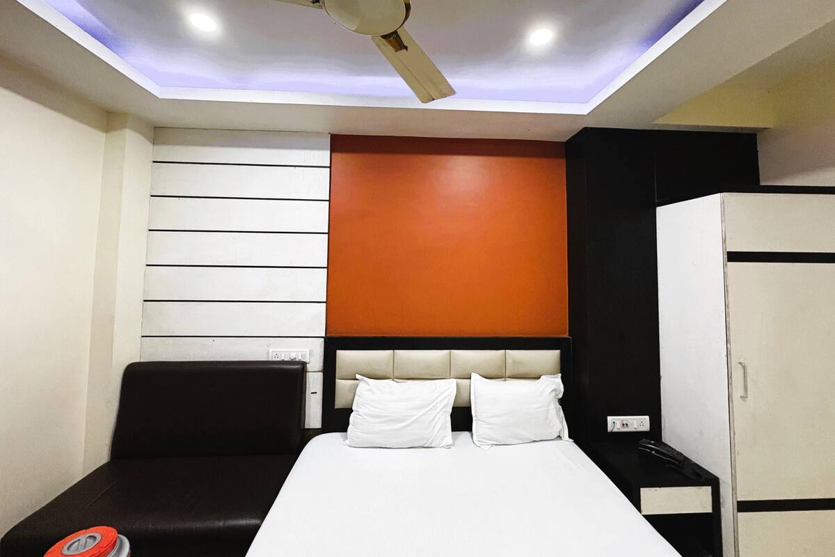 A hotel room with a bed, a ceiling fan, a wardrobe, and a wall with horizontal panels.