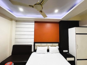 A hotel room with a bed, a ceiling fan, a wardrobe, and a wall with horizontal panels. - Beach Side Hotels Big boss (Digha)