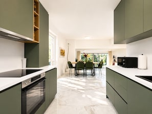 A modern kitchen with a central island, built-in appliances, and a dining area with a view.