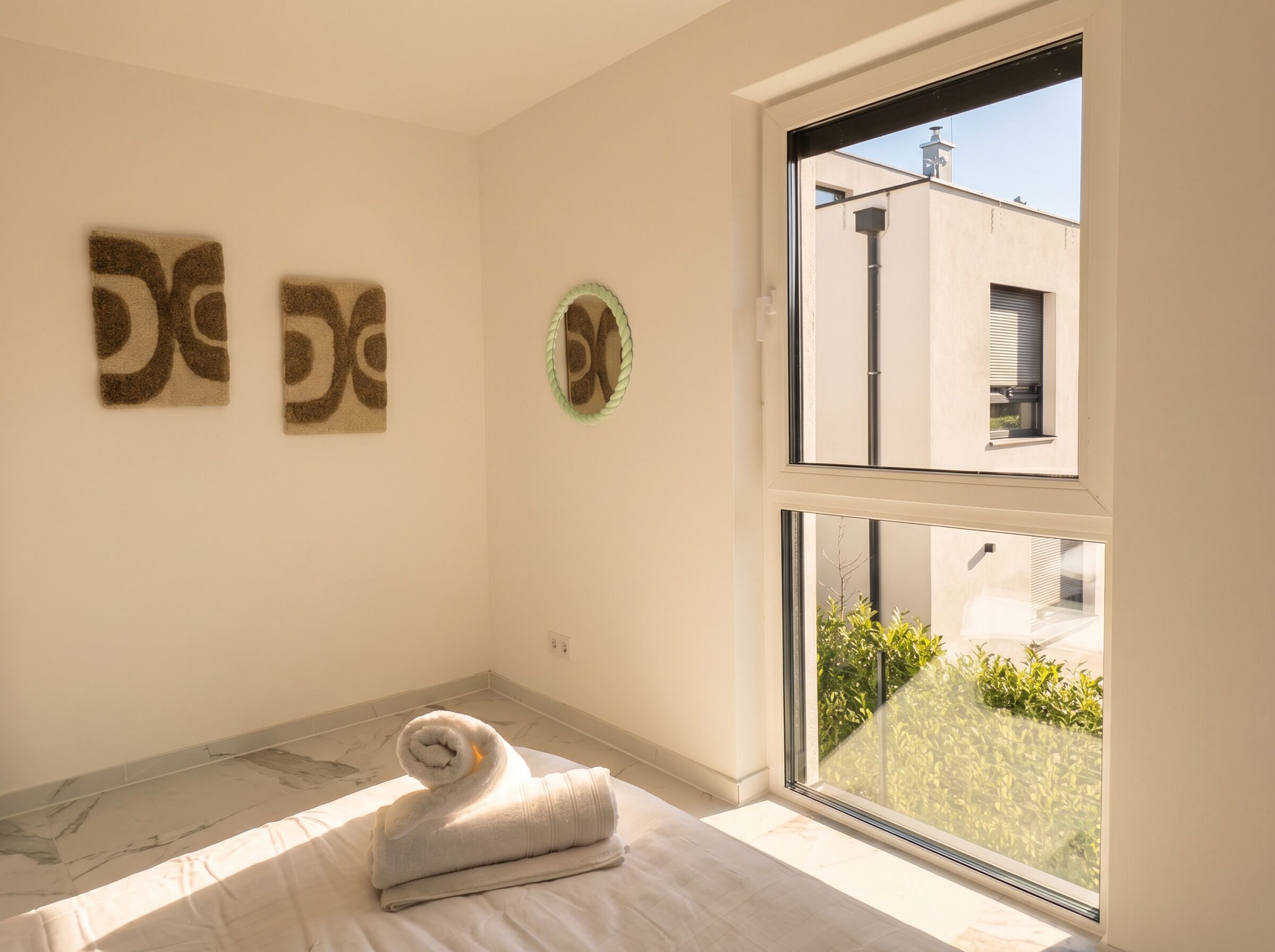 A room with a bed, a window, and two wall art pieces.