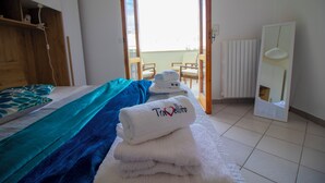 A hotel room with a bed, a chair, a table, and a view of the outside. - Charming Holiday House With Ocean Views in Otranto (Otranto)