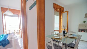 A dining area with a glass table, white chairs, and a view of the outside. - Charming Holiday House With Ocean Views in Otranto (Otranto)