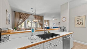 A modern kitchen with a sink, dishwasher, and wooden countertop. - Marsh Breeze Hideaway at Masters Place (Pawleys Island)