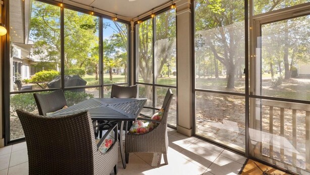 A covered patio with a table and chairs, large windows, and a ceiling fan. - Marsh Breeze Hideaway at Masters Place (Pawleys Island)
