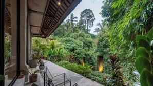 A lush garden with a concrete pathway, potted plants, and metal chairs. - Pager Apartments 2BR in Ubud Center (Ubud)
