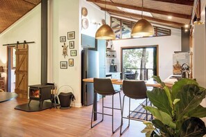 A modern kitchen with a central island, pendant lighting, and a large window. - Rhulani Lodge ~ sauna, spa, pizza oven, fireplace (Eudlo)