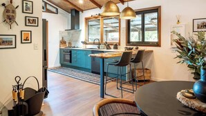 A modern kitchen with blue cabinets, a wooden island, pendant lights, and a dining area with a round table and chairs.