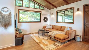 A cozy living room with a sofa, coffee table, and large windows.