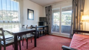 Ein Hotelzimmer mit Esstisch, Stühlen, Fernseher, Balkon und Blick.