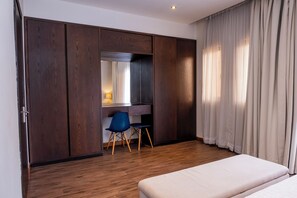 A bedroom with a bed, a desk with a chair, and a wardrobe. - Fallsway Palms (Lusaka)