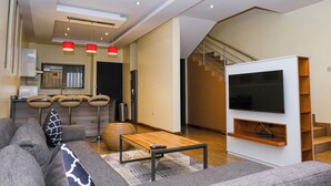 Ein modernes Wohnzimmer mit einer Couch, einem Couchtisch, einem Fernseher und einer Treppe.