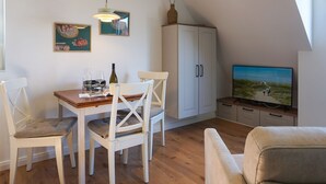 En matplats med ett bord och stolar, en tv och ett skåp.