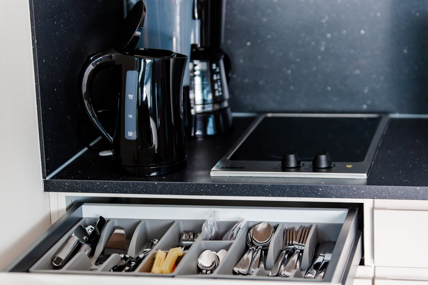 Une cuisine équipée d’une machine à café, d’un grille-pain et d’un organiseur de tiroir contenant des ustensiles.