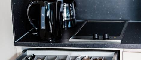 Une cuisine équipée d’une machine à café, d’un grille-pain et d’un organiseur de tiroir contenant des ustensiles.