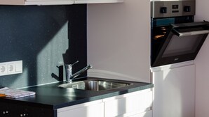 A modern kitchen with a stainless steel sink, white cabinets, and a built-in oven. - Kranichnest Schwimmhaus - Kranichnest Schwimmhaus: lake view, terrace, wood-burning stove (Ribnitz-Damgarten)