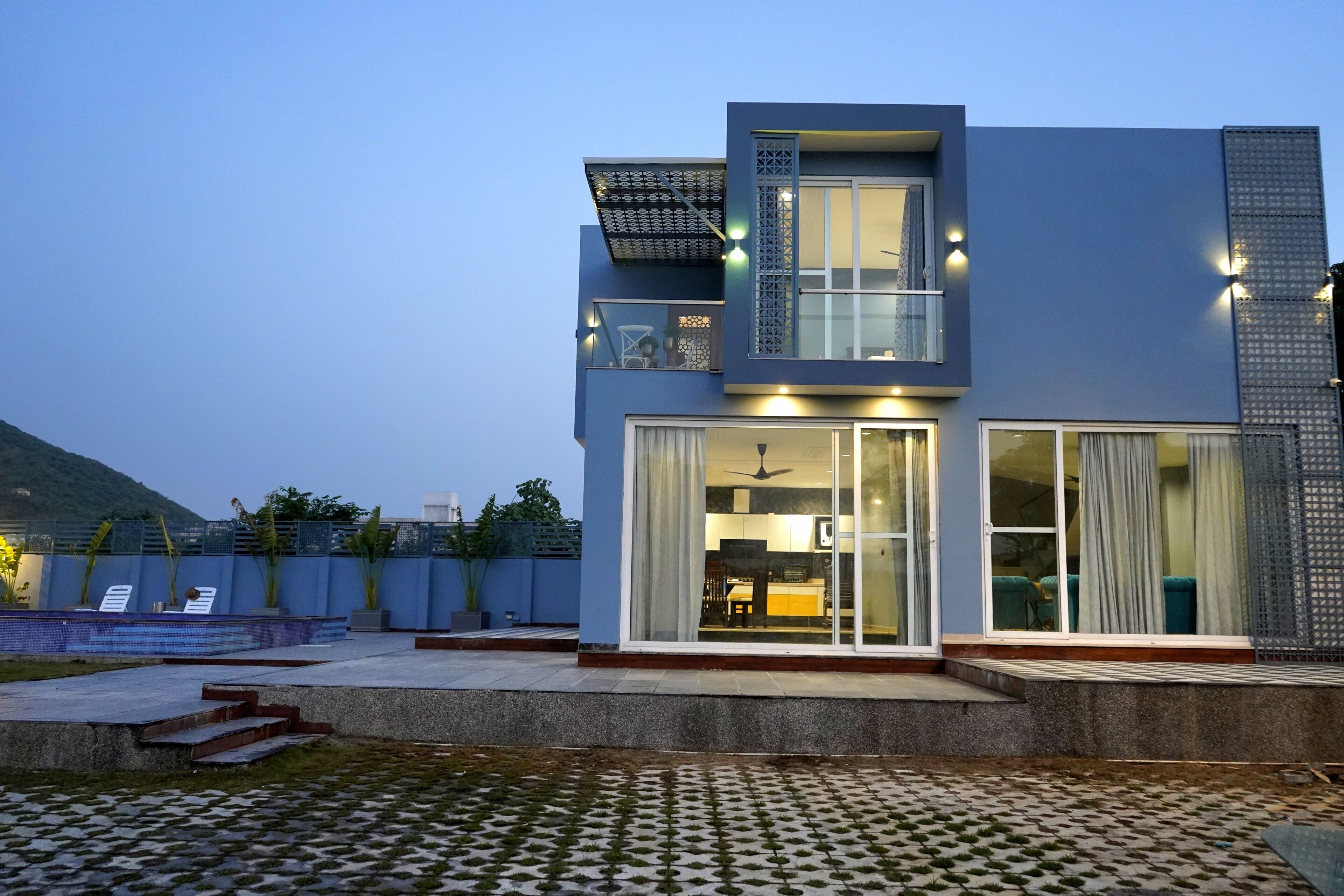 Un bâtiment moderne à deux étages, doté de grandes fenêtres, d’un balcon et d’un toit plat.