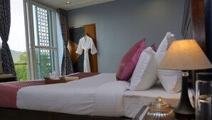 Een hotelkamer met een bed, een nachtkastje met een lamp, een vaas en een raam met gordijnen.