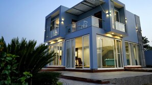 Een modern, tweelaags gebouw met grote glasramen, een balkon en een plat dak met een dakraam.