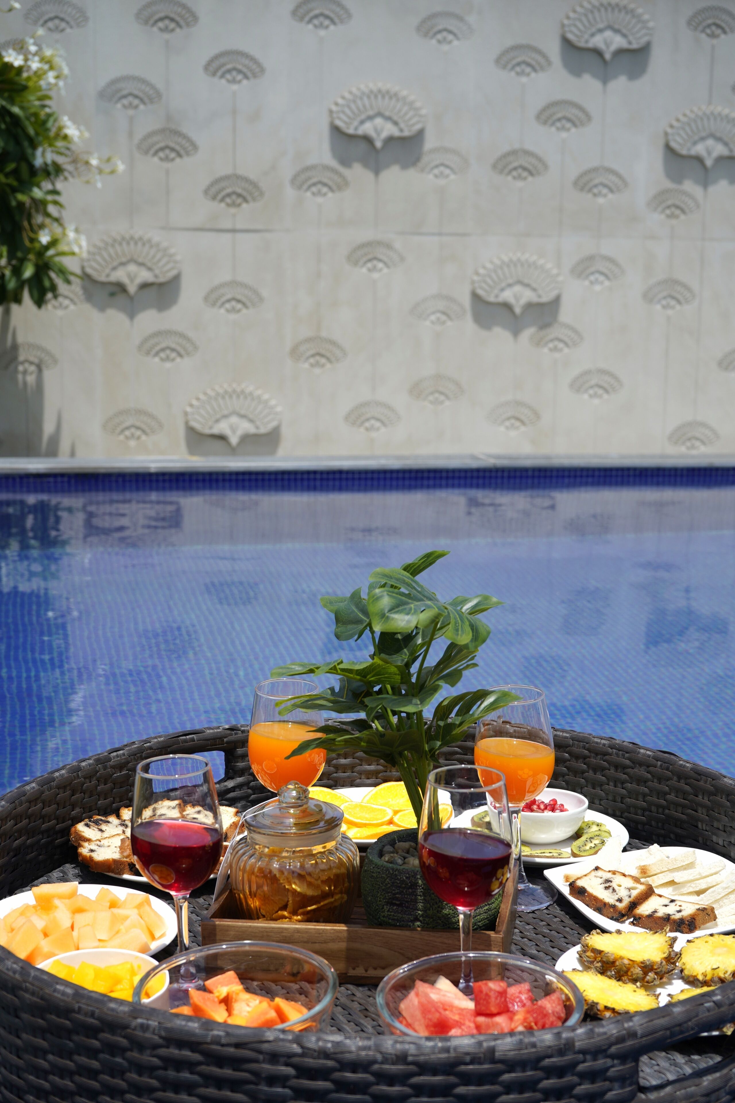 Un plat de petitdejuni amb diferents aliments i begudes al costat d'una piscina.
