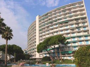 Ein mehrstöckiges Hotel mit Balkonen, einem Schwimmbad und umgebender Bepflanzung.