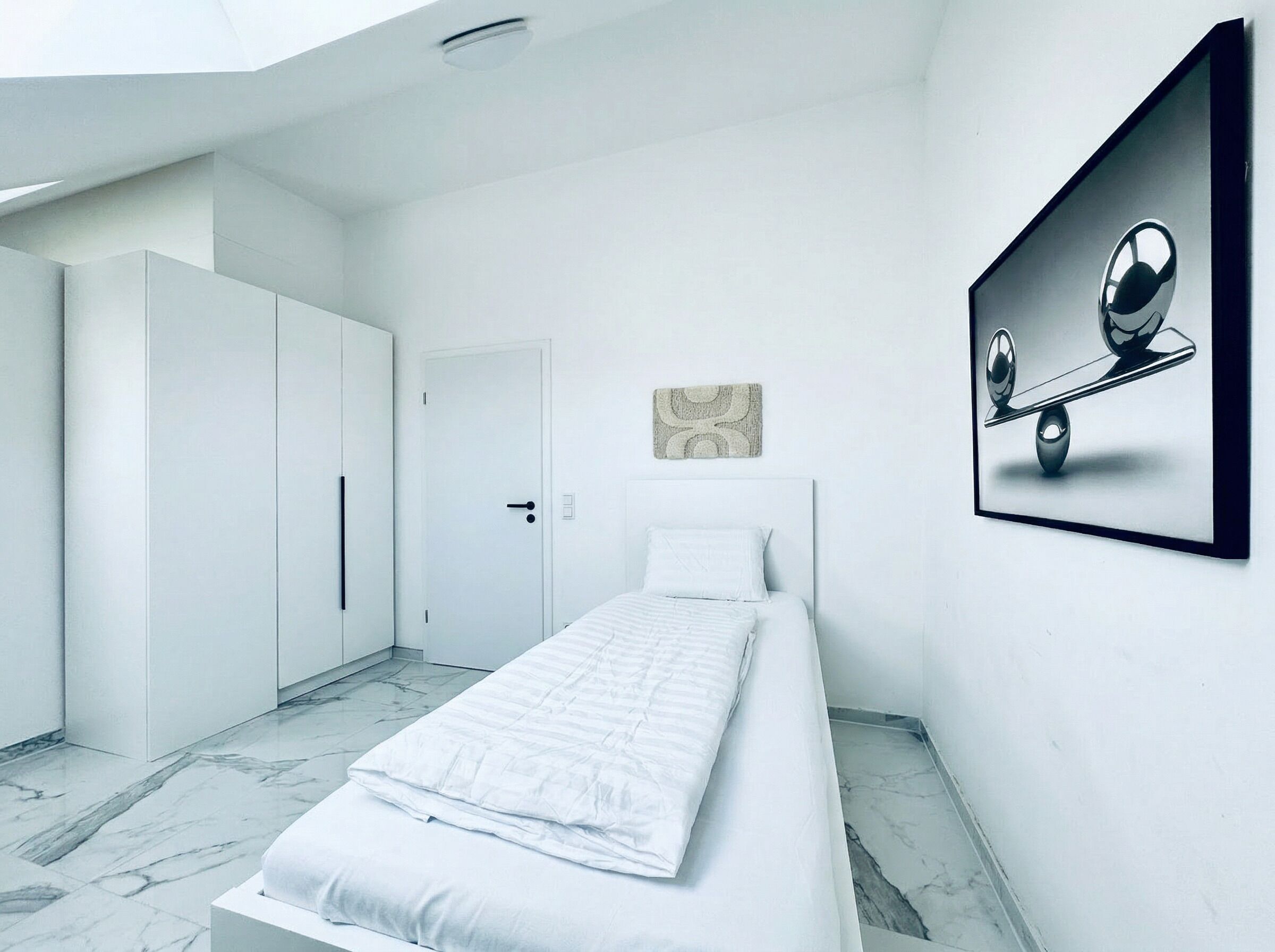 Une chambre moderne comprenant un lit, une armoire, une porte et une œuvre d’art accrochée au mur.