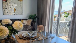 Tavola imbandita per quattro con vista mare, un lampadario moderno e un'opera d'arte contemporanea appesa al muro.