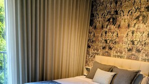 Camera moderna con un letto grande, una parete decorata e vista su spazi verdi.