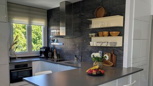 Una cucina moderna con isola centrale, mobili bianchi e una parete rivestita in pietra.