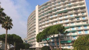 A multi-story hotel with balconies, a swimming pool, and surrounding greenery. - Convenient Beachside Studio With Pool (Lignano Sabbiadoro)