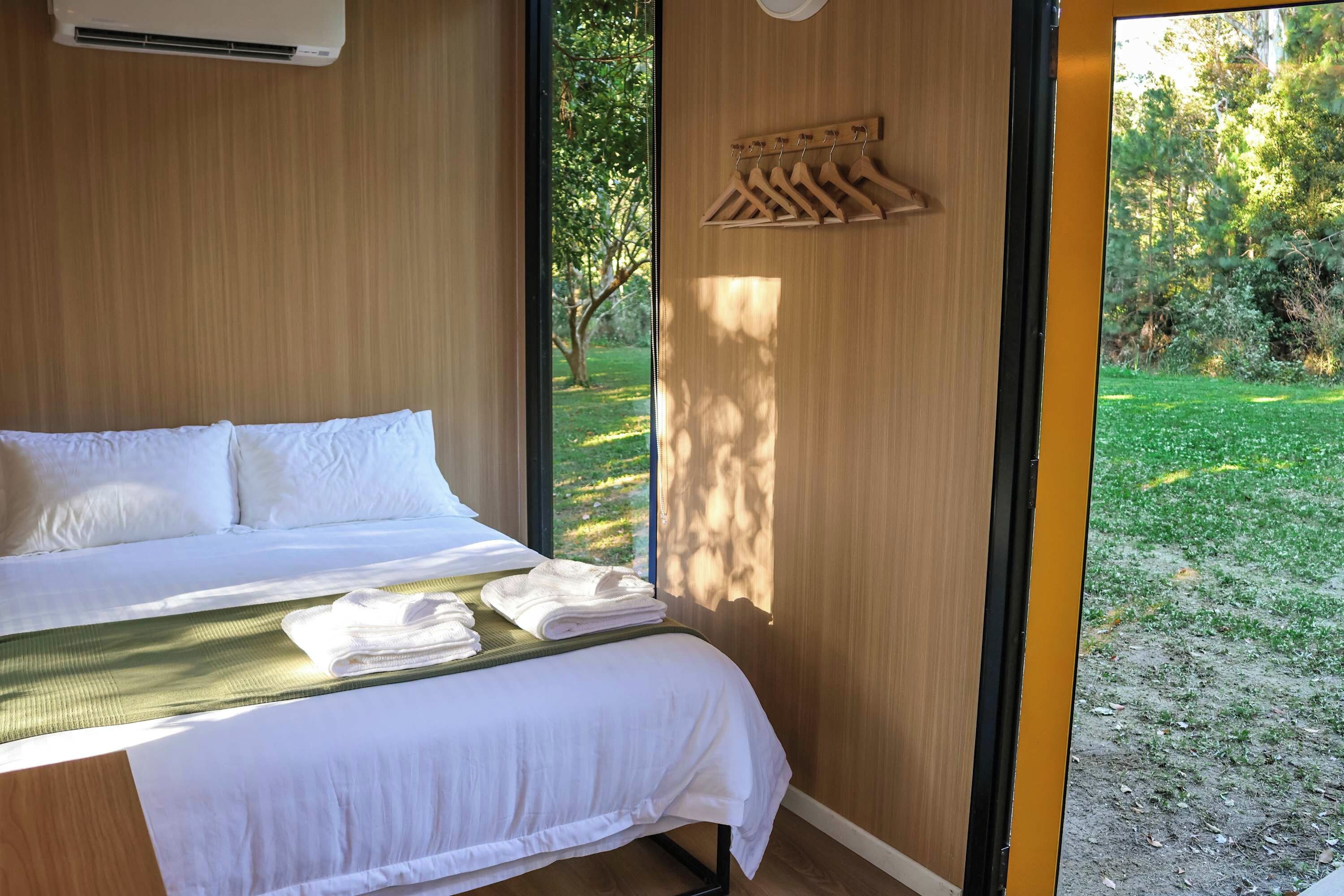 A bedroom with a bed, a window, and a view of a garden.