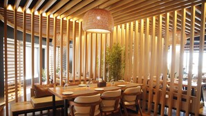 A dining area with a wooden table, chairs, and a hanging light fixture. - Hotel Subansiri (Dibrugarh)