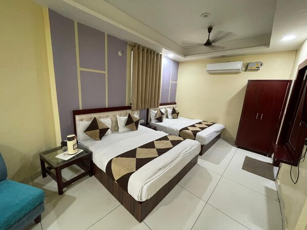A hotel room with two beds, a nightstand, a wardrobe, and an air conditioning unit.