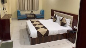 Ein Hotelzimmer mit einem großen Bett, einem Schreibtisch, einem Sessel und einem kleinen Tisch.