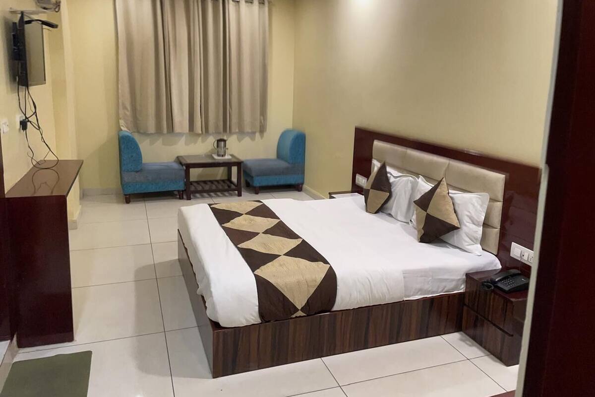 Ein Hotelzimmer mit einem großen Bett, einem Schreibtisch, einem Sessel und einem kleinen Tisch.