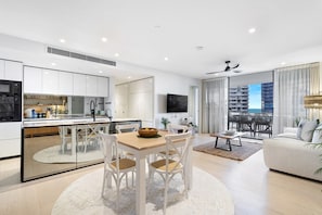 Eine moderne Wohnung mit Küche, Essbereich, Wohnzimmer und Balkon mit Blick auf die Stadt.