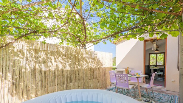 Área externa com hidromassagem, cercada por um bambuzal, mesa com cadeiras e vista para a casa.