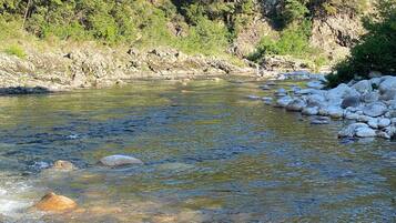 A river with clear water, surrounded by rocks and greenery.