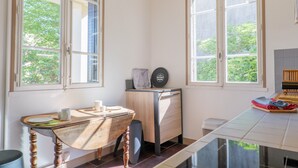 Cozinha com duas janelas, uma mesa de madeira, um armário pequeno e painel de azulejos.