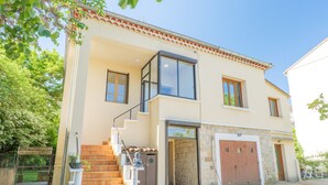 Uma casa de dois andares com escadas, garagem e porta que dá para uma área coberta.
