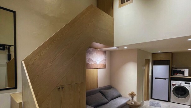 A modern interior with a staircase, a sofa, a small table, and a washing machine.
