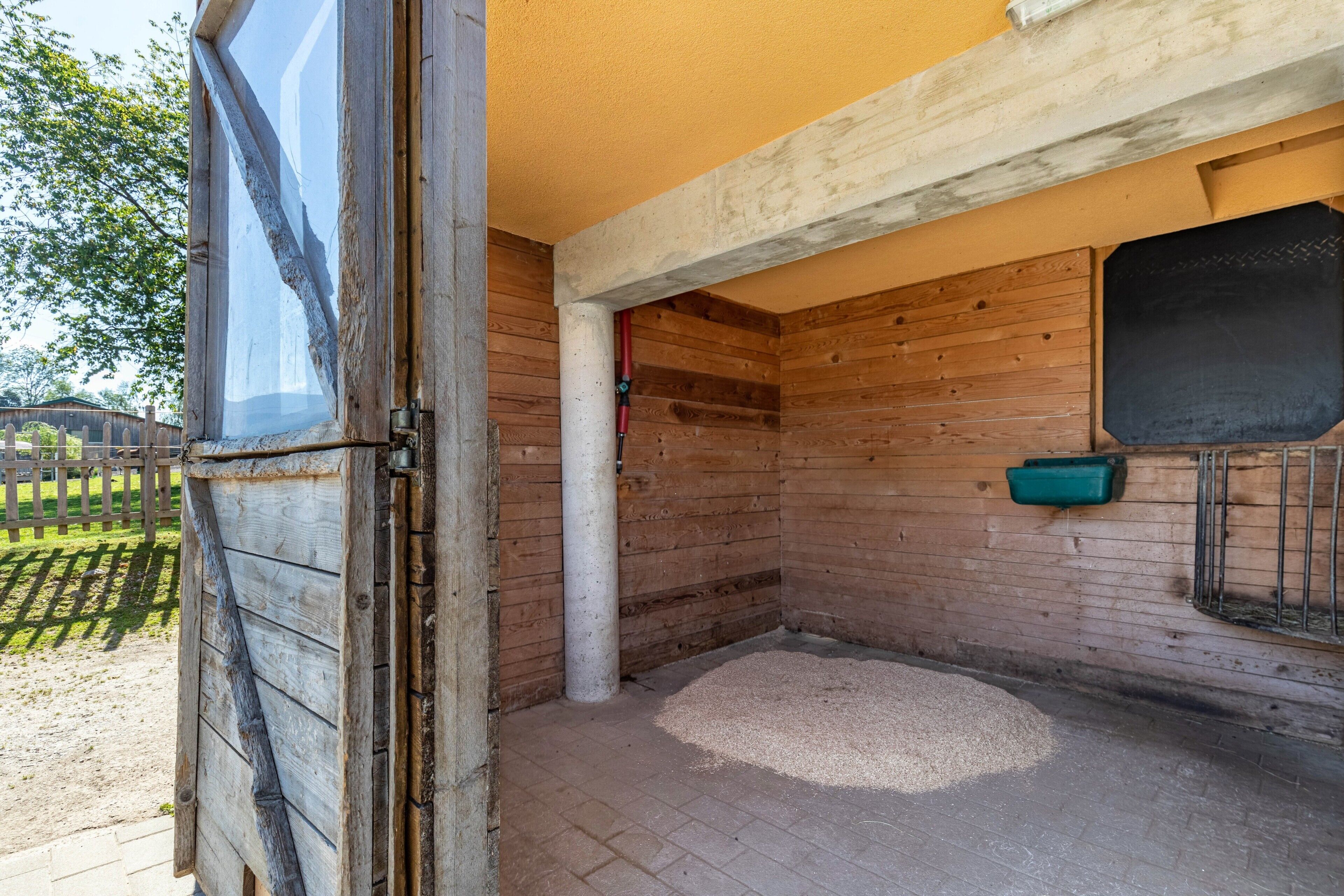 A wooden interior with a window, a feeding trough, and a brick floor.