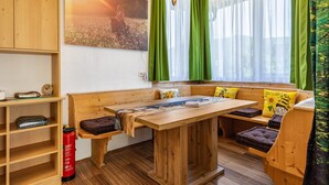 Quarto de madeira com um banco, uma mesa e um sofá com almofadas.