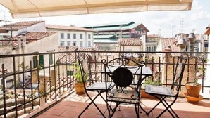 A balcony with a table and chairs, potted plants, and a view of buildings. - Apartment with a terrace overlooking the Duomo in the heart of Florence (Firenze)