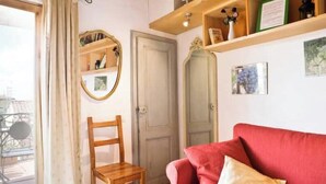 A room with a red sofa, a wooden chair, a mirror, and a door. - Apartment with a terrace overlooking the Duomo in the heart of Florence (Firenze)