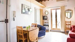 A room with a wooden dining table, blue sofa, red sofa, and a TV on a shelf. - Apartment with a terrace overlooking the Duomo in the heart of Florence (Firenze)